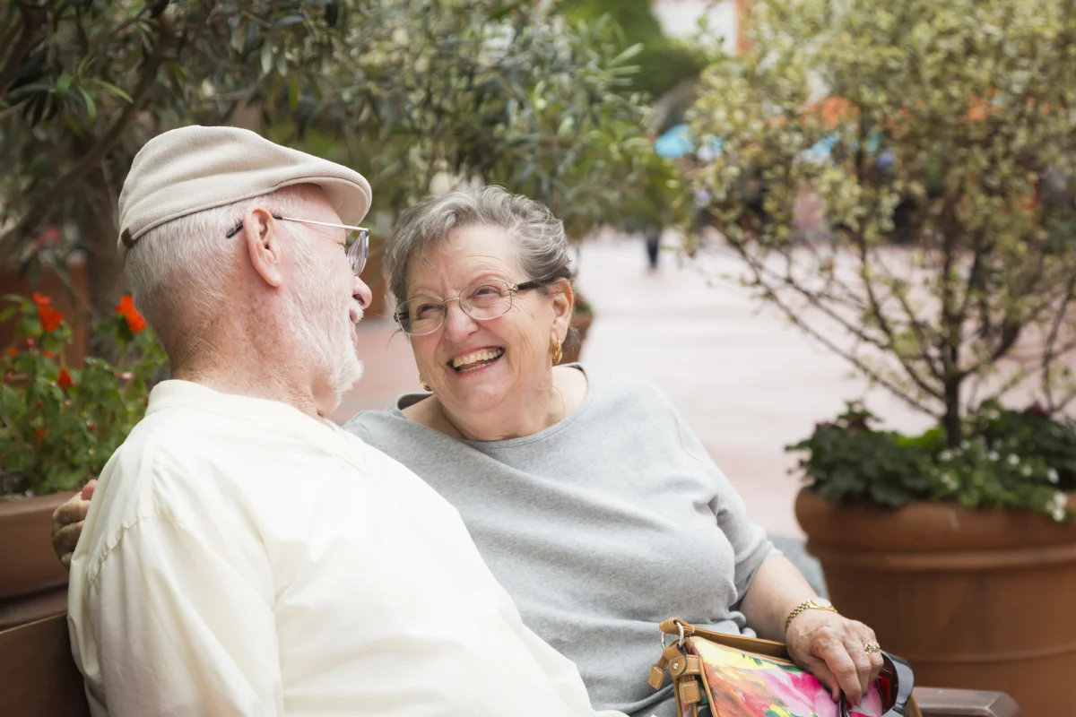 happy senior couple resting on a bench in the courtyard