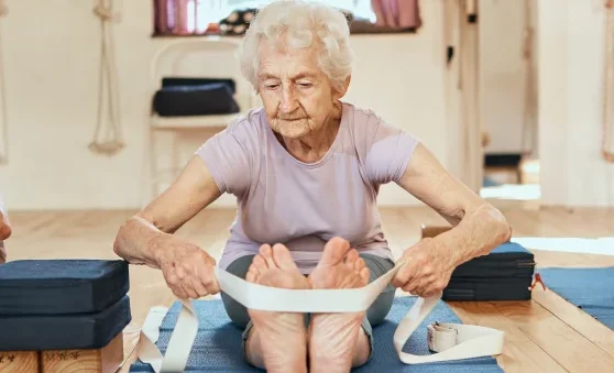 group of seniors stretching with yoga strap during instructor led yoga class